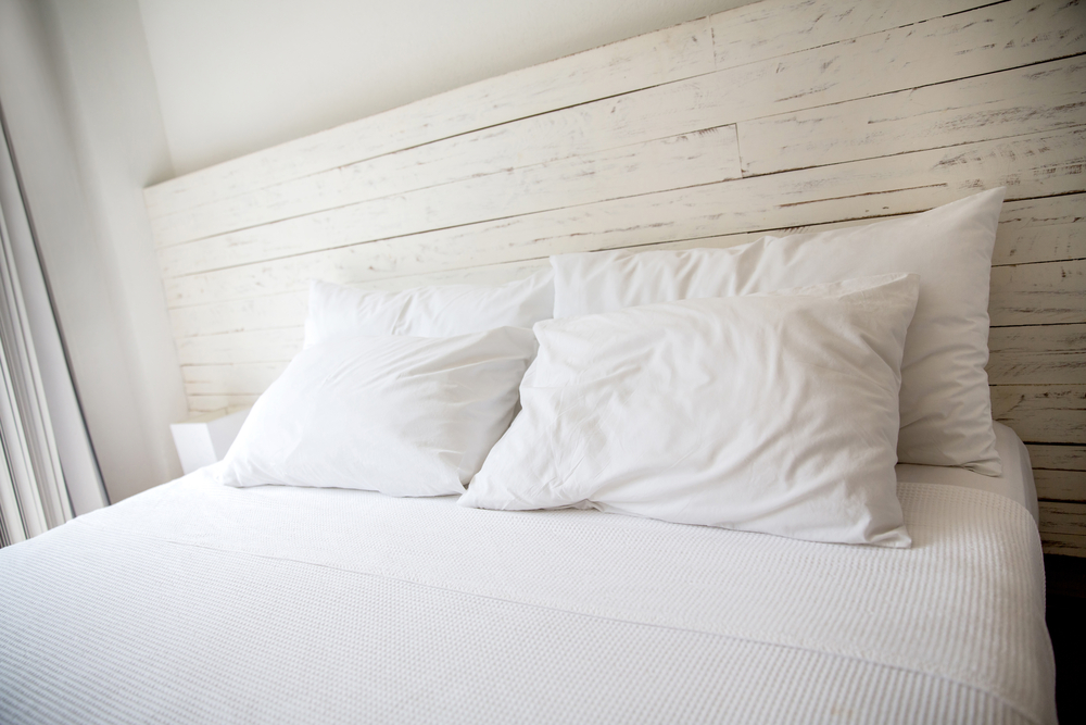 White bedroom with a king size bed and pillows.