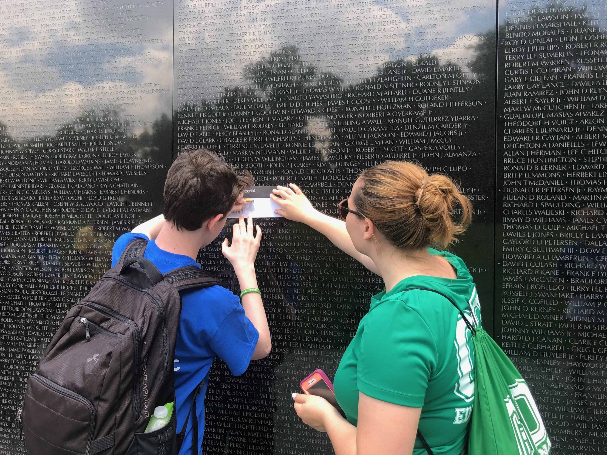student doing a rubbing at the Vietnam war memorial