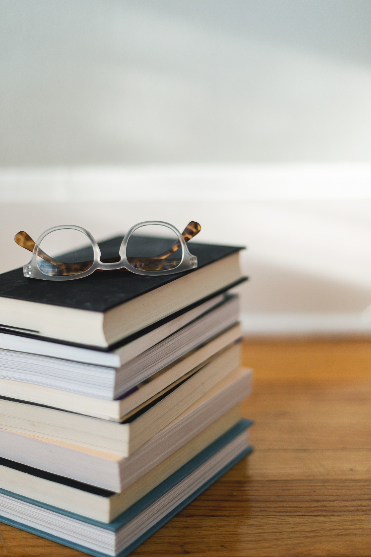 Stacked books with glasses on top at a library. 